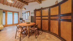 Un espace repas comprenant une table et des chaises en bois, une grande cloison en bois et un plafond avec des poutres apparentes.