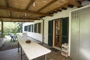 A covered patio with a table and chairs, a basket, and a metal storage unit. - CASA I FORNI ( EX SASSI TURCHINI) - BILO CASA I FORNI ( SASSI TURCHINI) (Porto Azzurro)