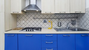 Una cocina con estufa a gas, un lavamanos y gabinetes azules.