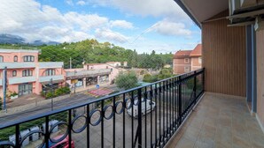 A balcony with a view of a town, including buildings and greenery.