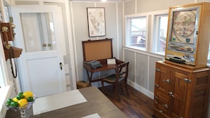 Une pièce avec un bureau en bois, un vieux juke-box, une carte accrochée au mur et une porte avec un téléphone.