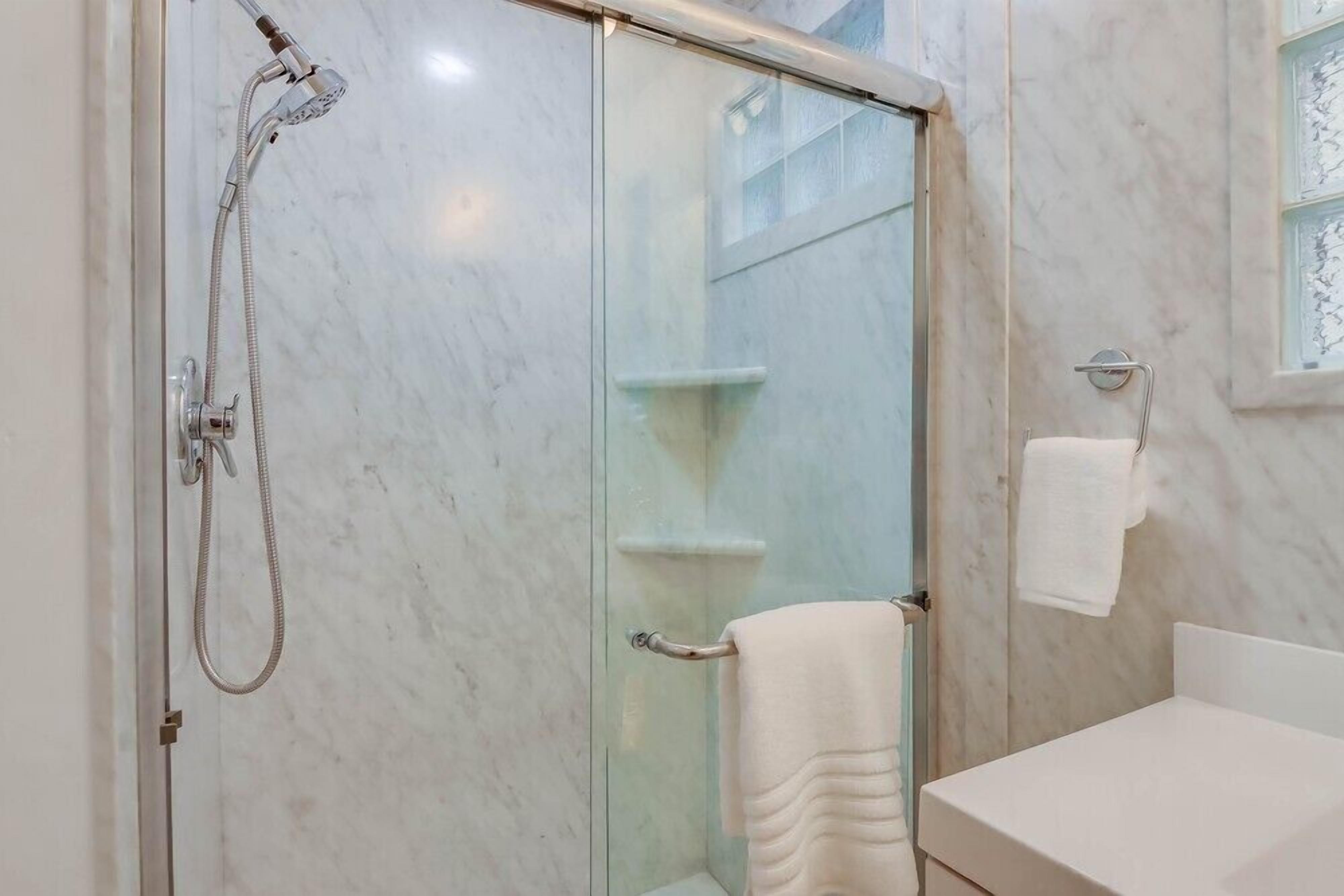 A bathroom with a glass-enclosed shower, a white sink, and a towel rack.