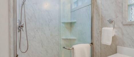 Ein Badezimmer mit einer gläsernen Duschkabine, einem weißen Waschbecken und einem Handtuchhalter.