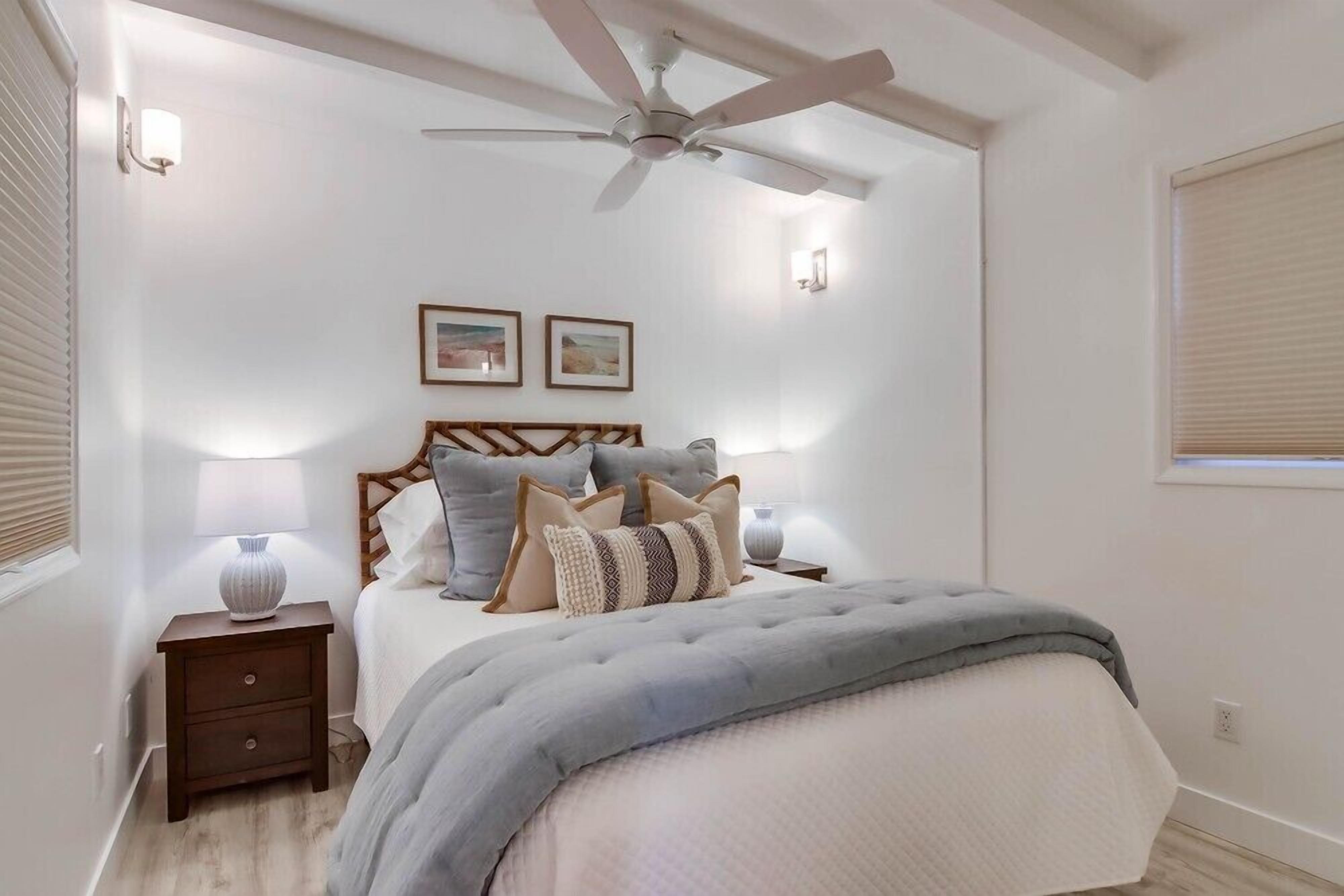 Ein Schlafzimmer mit Bett, Nachttischen, Deckenventilator und Wandleuchten.