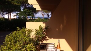 An outdoor dining area with a table set for two, a bottle of wine, and a view of the sea.