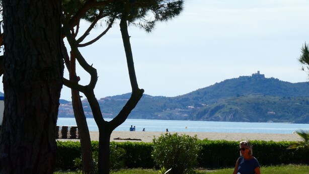 A beach with a castle on a hill in the background.