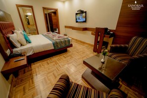 A hotel room with a bed, a TV, a sofa, and a coffee table.