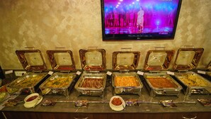 Un bufé con diferentes opciones de comida y una televisión mostrando un evento de baile.