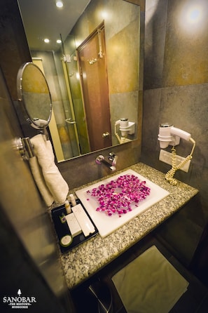 A bathroom with a granite countertop, a white sink, a mirror, a hairdryer, and a towel rack.