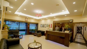Vestíbulo de hotel con mostrador de recepción, zona de estar y escalera que conduce a otras plantas.