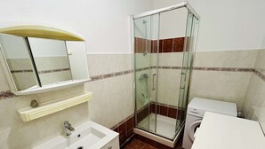 Une salle de bain avec une douche à parois de verre, un lavabo avec un miroir et des toilettes.