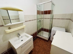 A bathroom with a glass-enclosed shower, a sink with a mirror, and a toilet.