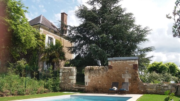 Una piscina con un muro de piedra y un banco.