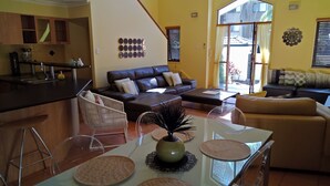 Un grand espace de vie comprenant une cuisine, une table à manger avec des sets de table, un canapé et un fauteuil.