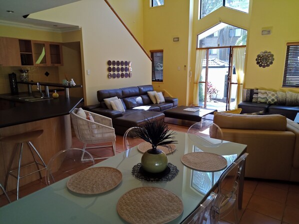 A spacious living area with a kitchen, a dining table with placemats, a sofa, and a chair.