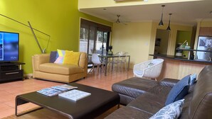 Un salon comprenant un canapé, une table basse et un téléviseur. Il y a également un coin repas avec une table et des chaises.