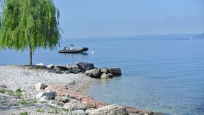 A calm lake with a small boat anchored near a rocky shore. - Holiday Apartments Brenzone - Apartment SOLE (Brenzone)