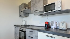 A modern kitchen with a gas stove, oven, microwave, coffee maker, and toaster. - Holiday Apartments Brenzone - Apartment SOLE (Brenzone)