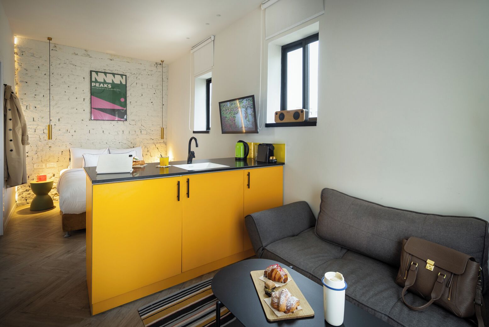 Un espace de vie compact comprenant un coin cuisine, un canapé, une table basse et un coin repas où sont servis des pâtisseries.