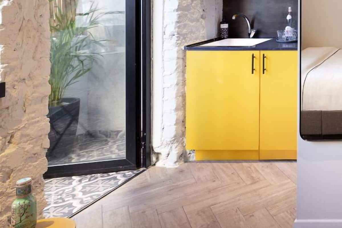 A modern kitchen with yellow cabinets and a black countertop.