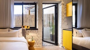 Une chambre avec un grand lit, une petite table ronde, une armoire jaune et une porte-fenêtre coulissante donnant sur un espace extérieur.