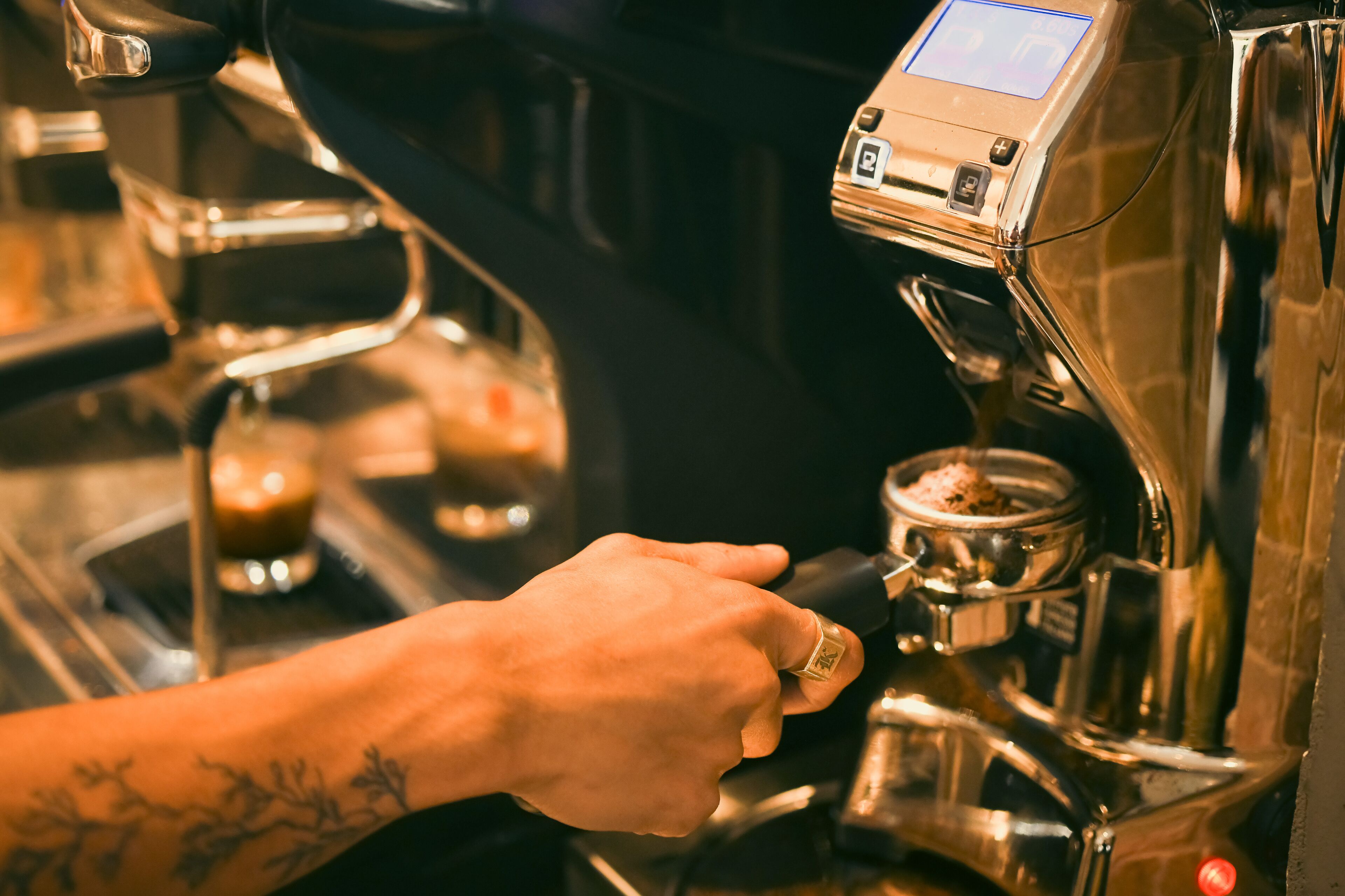 A hand operating a coffee machine with a digital display.