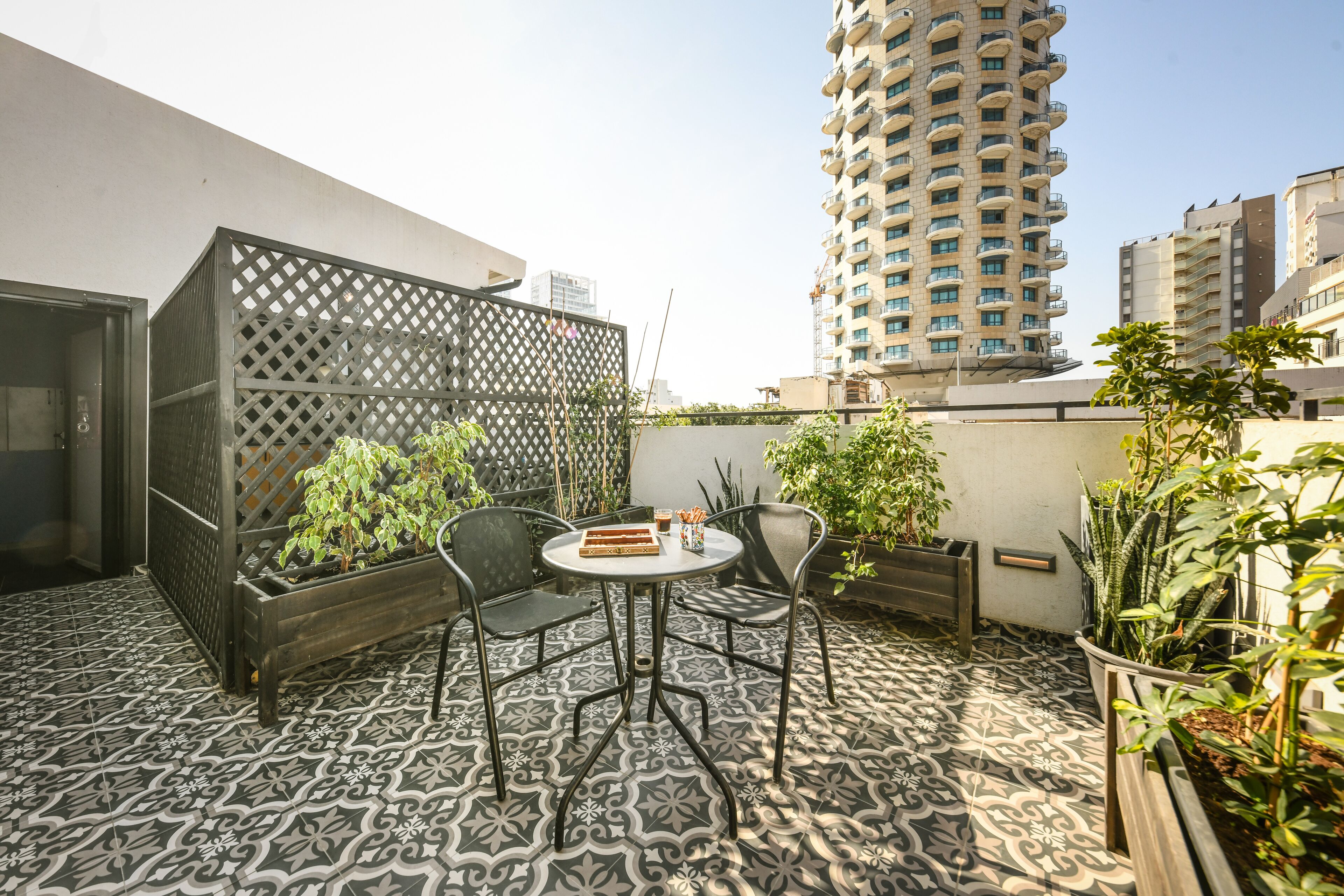A rooftop patio with patterned flooring, a round table, and chairs.