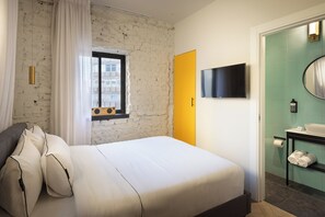 A hotel room with a bed, a window, a television, and a bathroom with a sink and mirror. - Silicate Ben Yehuda - Smart Hotel by Loginn Tel Aviv (Tel Aviv)