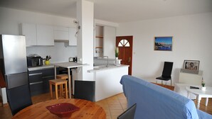 A modern kitchen with white cabinets, a built-in microwave, and a dining area with a wooden table and chairs.