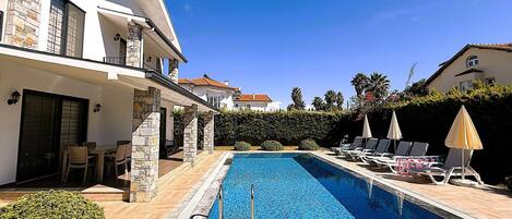 Una piscina al aire libre, sillones reclinables de piscina