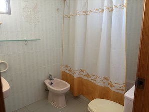 A bathroom with a toilet, bidet, and a glass shelf.