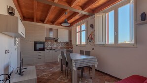 A modern kitchen with wooden beams, a dining table, and a red sofa.