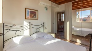 A bedroom with a bed, a painting, and a window.