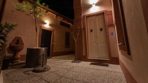 A courtyard with a door, a potted plant, and a metal sculpture.