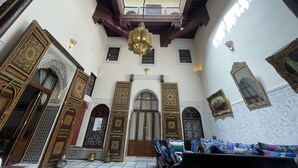 An interior with ornate wooden doors, a central chandelier, and a skylight. - Rent room at Riad Alkatib in the heart of the Medina Meknes (MEKNES)
