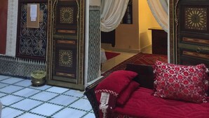 A traditional Moroccan interior with ornate doors, a bed with red and white pillows, and a tiled floor. - Rent room at Riad Alkatib in the heart of the Medina Meknes (MEKNES)