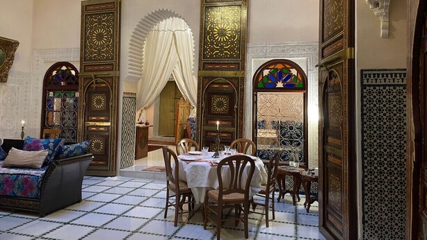 A traditional Moroccan interior with a dining area, ornate doors, and a sofa. - Rent room at Riad Alkatib in the heart of the Medina Meknes (MEKNES)