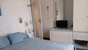 Une chambre à coucher comprenant un lit, une commode, un téléviseur et une porte ornée d’un panneau décoratif.