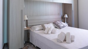 A bedroom with a bed, two bedside lamps, a headboard, and a patterned floor.