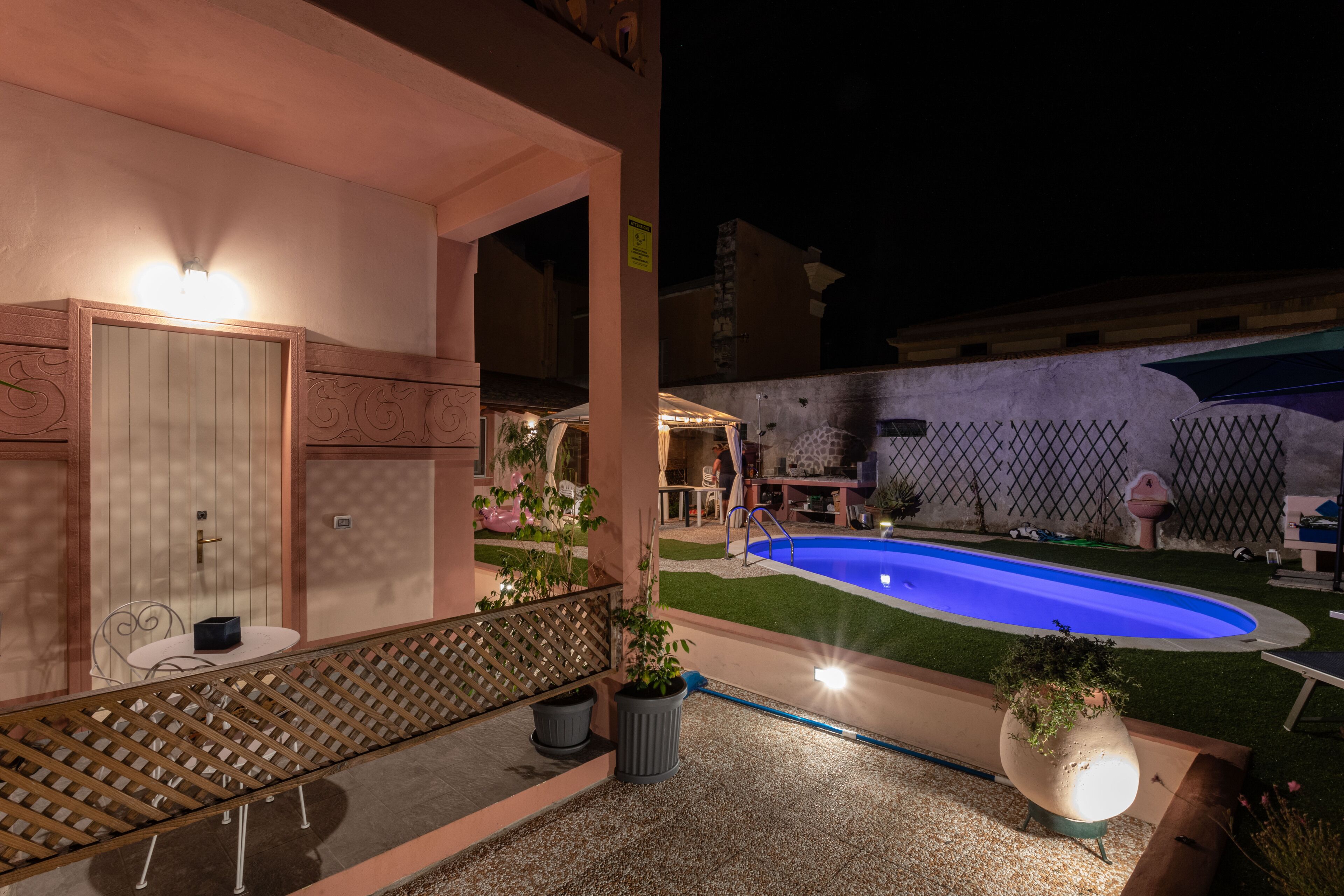 A pool area with a blue pool, a wooden deck, and a seating area with a table and chairs.