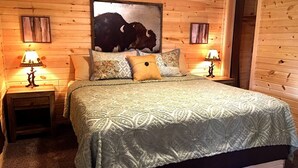 Una camera da letto con pannelli di legno, un letto grande, due lampade sui comodini e un quadro con un bufalo al muro.