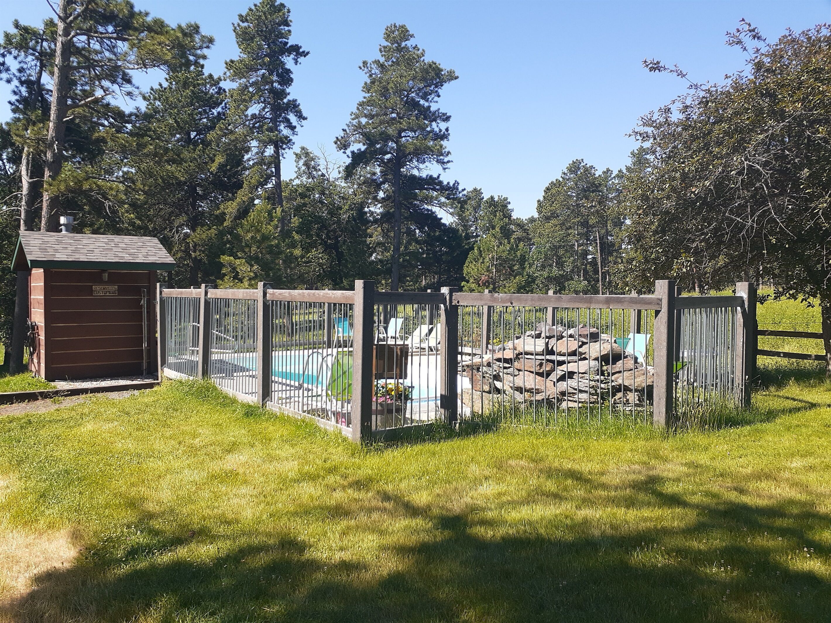 A pool area with a wooden fence, a small building labeled 'RESERVATION', and a stone wall.