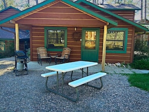 Rustic cabin-style building with a covered patio area featuring a picnic table and grill.