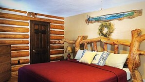 A log cabin-style bedroom with a wooden bed, a door, and a wall-mounted artwork.