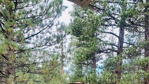 Un espacio de patio al aire libre con mobiliario de mimbre, incluyendo un sofá y sillas, una mesita de centro y una sombrilla.