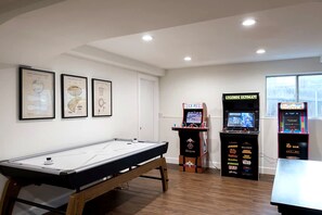 Ein Zimmer mit Billardtisch, Spielautomaten und gerahmten Gegenständen an der Wand.