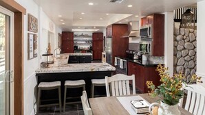Una cocina moderna con una isla grande, armarios de madera oscura y una pared decorativa de piedra.