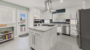 A modern kitchen with white cabinetry, stainless steel appliances, and a central island. - Preston Hollow Retreat (Dallas)