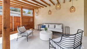 An outdoor patio with a wooden pergola, a round white table, and metal chairs. - Preston Hollow Retreat (Dallas)
