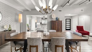 A modern dining area with a large wooden table, upholstered chairs, and a central chandelier. - Preston Hollow Retreat (Dallas)